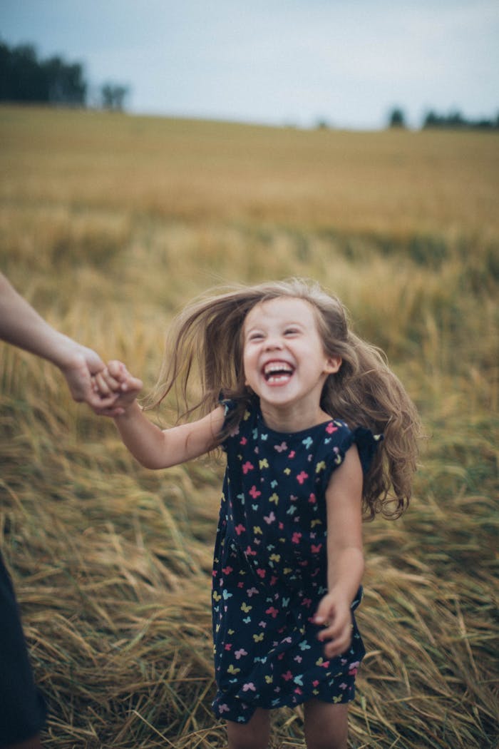 Joyful girl laughing and playing in a golden wheat field outdoors.